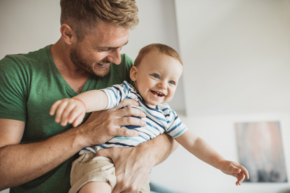 Father playing on bed with his young song, it's weekend and they enjoy in time together. Father carrying son