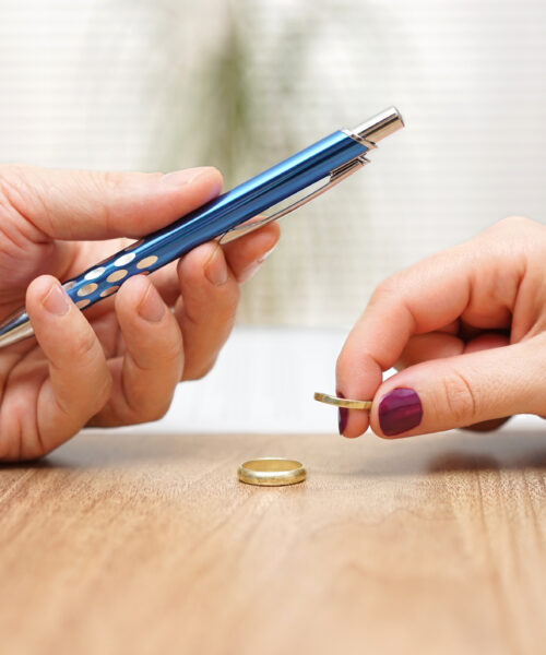 Husband is giving pen to sign divorce papers his former wife after he take off the ring form finger