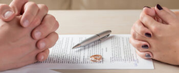 hands of wife and husband signing divorce documents or premarital agreement