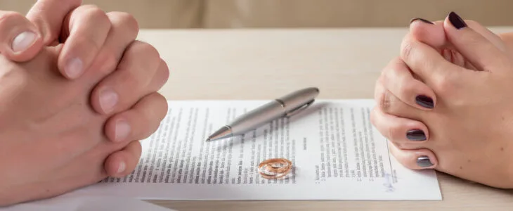 hands of wife and husband signing divorce documents or premarital agreement